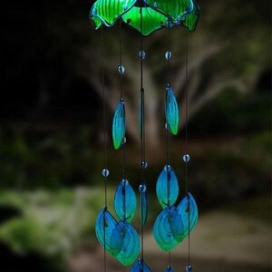 A solar-lit glass peacock tail wind chime with blue and green glass elements and a glowing blue ball at the bottom.