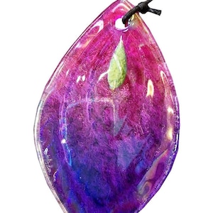 A colorful, multicolored stone or gemstone with a green leaf attached, hanging from a string.