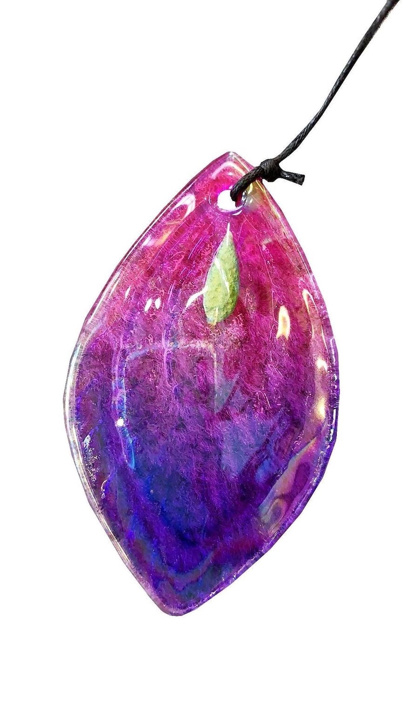 A colorful, multicolored stone or gemstone with a green leaf attached, hanging from a string.