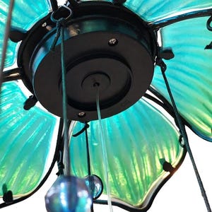 a close-up view of a decorative light fixture with a green and blue color scheme. The fixture appears to be made of glass or a similar material, with a black base and a circular light at the center.