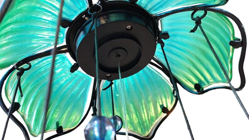a close-up view of a decorative light fixture with a green and blue color scheme. The fixture appears to be made of glass or a similar material, with a black base and a circular light at the center.