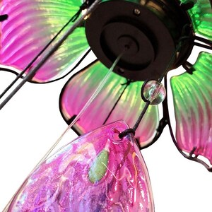 A close-up view of a colorful glass ornament with a metallic frame, featuring a combination of green, pink, and purple hues.