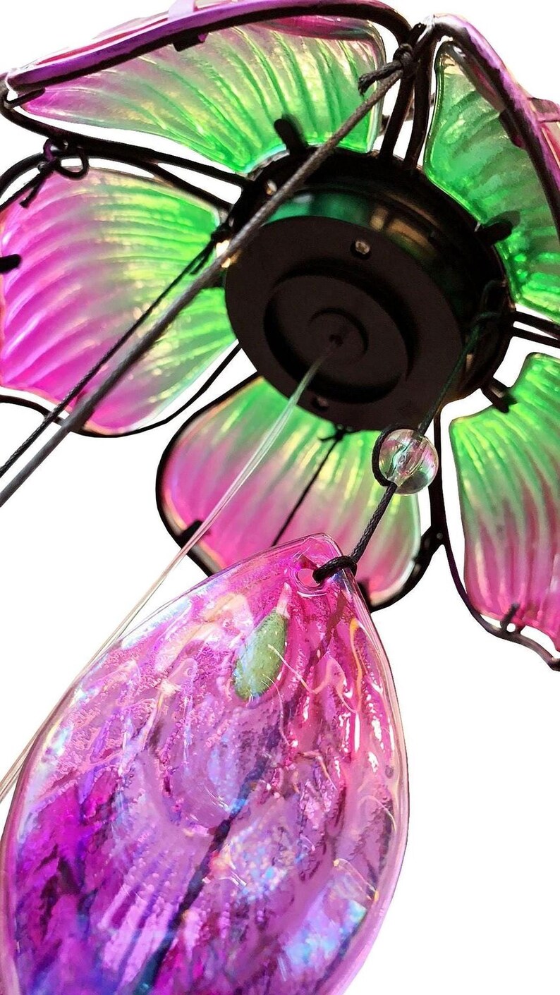A close-up view of a colorful glass ornament with a metallic frame, featuring a combination of green, pink, and purple hues.
