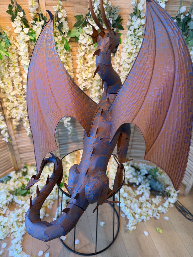 a large, metallic dragon sculpture with intricate details and a metallic appearance.