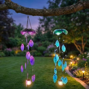two wind chime decorations hanging from a tree branch in a garden at night. The decorations are colorful and illuminated, creating a festive and enchanting atmosphere.