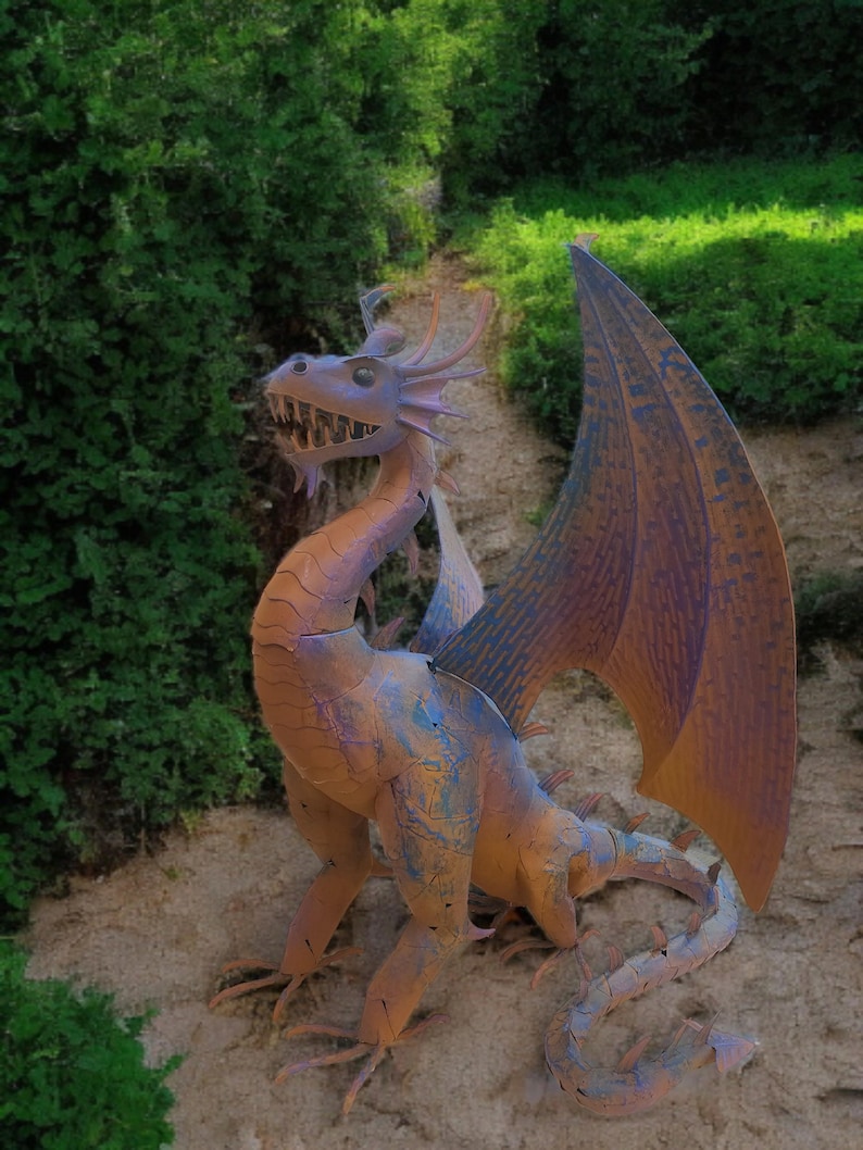 A colorful dragon statue stands on a dirt path surrounded by lush greenery.