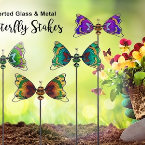 May include: Four colorful glass and metal butterfly garden stakes. The butterflies are in shades of purple, green, and orange. The stakes are inserted into the ground.