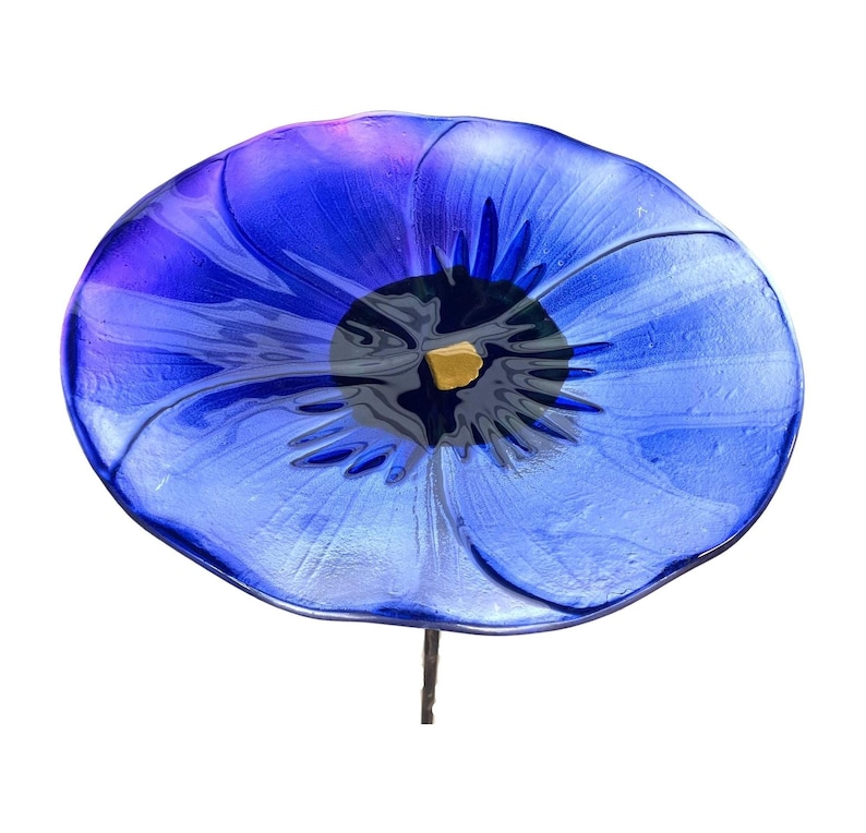 A large, vibrant blue glass flower with a yellow center is the central focus of the image.