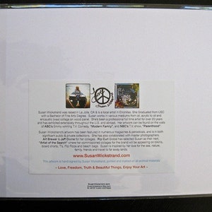 May include: A white card with a colorful image of a peace sign and a woman in a boat. The card has text about the artist, Susan Wickstrand, and her artwork. The text includes her website address, www.SusanWickstrand.com, and the phrase "Love, Freedom, Truth & Beautiful Things, Enjoy Your Art."