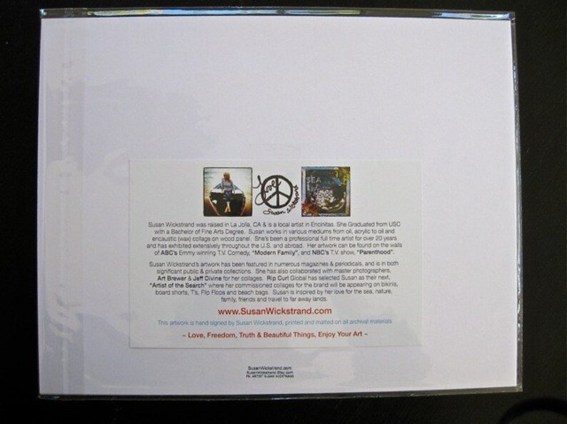 May include: A white card with a colorful image of a peace sign and a woman in a boat. The card has text about the artist, Susan Wickstrand, and her artwork. The text includes her website address, www.SusanWickstrand.com, and the phrase "Love, Freedom, Truth & Beautiful Things, Enjoy Your Art."