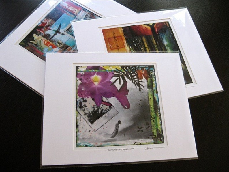 May include: Three white matted prints with different images. The top print features a colorful abstract design with a bird in flight. The middle print features a close-up of a purple orchid with green leaves. The bottom print features a colorful abstract design with a red and yellow color scheme.