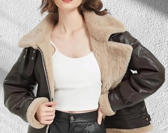 May include: A brown leather jacket with a shearling collar and lining. The jacket has a zipper closure and two pockets on the front.