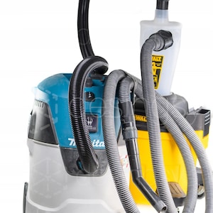 Könnte beinhalten: Ein türkisfarbener und grauer Makita-Staubsauger vor einem gelben DeWalt-Staubsauger mit einem weißen Zyklon-Staubabscheider, verbunden durch schwarze und graue flexible Schläuche. Die Geräte verfügen über Netzschalter und Markennamen.