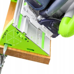 May include: A bright green and silver track saw guide rail accessory attached to a wooden board. The guide features a printed angle indicator labelled F 30 degrees with plus and minus adjustment symbols. A metal clamp is secured to the side.