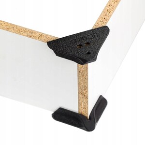 Puede incluir: Una pieza de esquina de aglomerado blanco con un soporte protector de plástico negro texturizado. El soporte tiene una superficie superior triangular con tres pequeñas hendiduras circulares y el texto STSC8 en relieve en el borde superior.