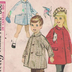 Könnte beinhalten: Simplicity Schnittmuster Nummer 5685 für Kindermäntel. Das Schnittmuster umfasst drei Designs: einen blau-weiß karierten Mantel, einen braunen Tweedmantel und einen roten Mantel. Das Schnittmuster ist für Größe 6.