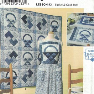 May include: A Simplicity Quilt Block Club pattern, lesson #3, featuring a basket and card trick. The pattern includes instructions for making a quilt, an apron, a chair cushion, and a table runner. The pattern is illustrated with a blue and white quilt, an apron, a chair cushion, and a table runner.