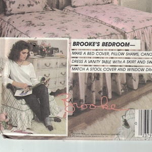 May include: A sewing pattern for a bedroom set, including a bed cover, pillow shams, canopy, vanity table skirt, swag, stool cover, and window drapes. The pattern is called "Brooke's Bedroom" and is from McCall's Crafts. The pattern number is 9133.