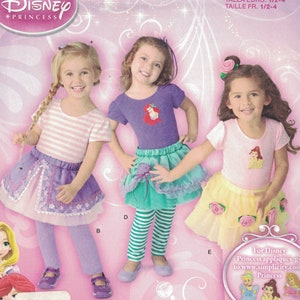 May include: A Simplicity sewing pattern for making Disney Princess costumes for girls. The pattern includes three different designs: a purple and white striped top with a purple skirt, a purple top with a green and white striped skirt, and a pink top with a yellow and white skirt. The pattern is for sizes 1/2-4.