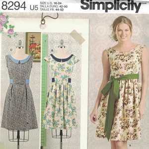 Peut inclure: Un patron de couture Simplicity pour une robe, numéro de modèle 8294, taille US 16-24, Talla Euro 42-50, Taille FR 44-52. Le patron montre trois styles différents de robes avec des imprimés floraux. La robe à gauche a un col bleu, la robe au milieu a un col noir et la robe à droite a une ceinture verte.