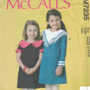 May include: McCall's sewing pattern for girls' dresses, sizes 2-3-4-5. The pattern includes two styles: a black and white polka dot dress with a pink collar and a blue dress with white lace trim.