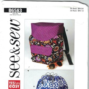 Könnte beinhalten: Ein Nähmuster für zwei Taschen. Die erste Tasche ist ein lila und blumiger Rucksack mit Kordelzug. Die zweite Tasche ist eine blaue und weiße Kordeltasche mit einem blauen Riemen. Das Muster heißt "see & sew" und ist mit "B6583" gekennzeichnet.