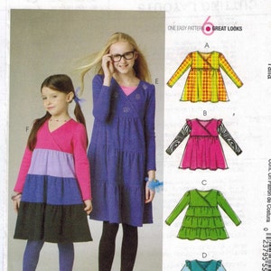 May include: Sewing pattern for a girl's dress with six different looks. The pattern is McCall's M6157 and is for sizes 3-4-5-6. The dress has a wrap style and is shown in different colors and patterns.