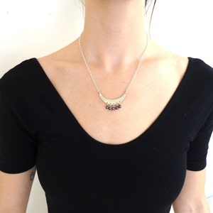 May include: A silver necklace with a crescent moon pendant and small purple gemstone accents.