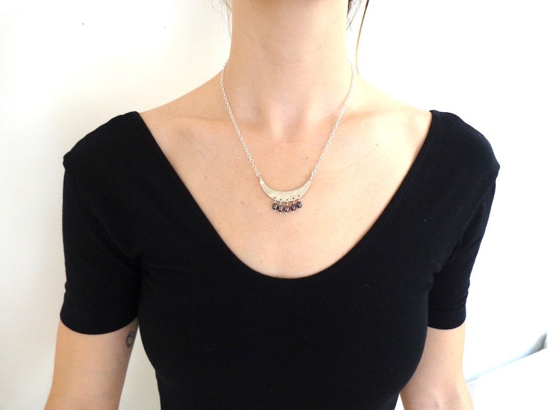 May include: A silver necklace with a crescent moon pendant and small purple gemstone accents.