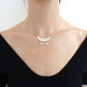 May include: A silver necklace with a crescent moon pendant and small pearl accents.