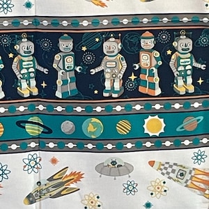 May include: A fabric print featuring a repeating pattern of retro-style robots, spaceships, and planets. The design includes horizontal bands of dark blue and teal, accented with white dots, atomic symbols, and stars on a white background.