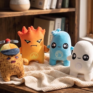 May include: Four plush toys featuring distinct designs: a brown textured character with a propeller hat, an orange character with a flame symbol, a light blue character with a water symbol, and a white character with a swirl symbol.