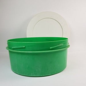 Peut inclure: Un récipient en plastique vert avec un couvercle blanc. Le récipient est rond et a une surface lisse. Le couvercle est également rond et a une surface lisse.