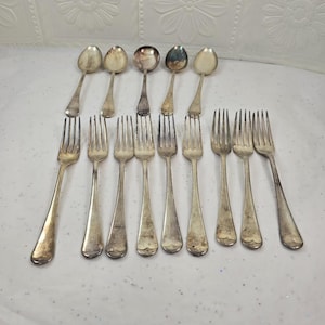 Può includere: Una collezione di posate d'epoca, tra cui cinque cucchiai e otto forchette. I cucchiai hanno coppette arrotondate e manici lunghi. Le forchette hanno quattro rebbi e un design del manico simile. Le posate sono in metallo color argento e mostrano segni di età.