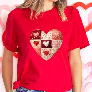Peut inclure: Un t-shirt rouge avec un motif de cœur en patchwork. Le cœur est composé de différents carrés de tissu, chacun avec un motif et une couleur différents, dont le rouge, le rose et le blanc. De petits appliqués en forme de cœur sont cousus sur le patchwork.
