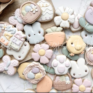 May include: A collection of pastel-colored Easter-themed sugar cookies decorated with various designs, including flowers, bunnies, chicks, and baskets.