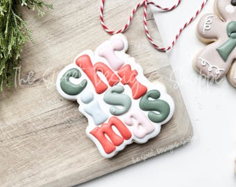 May include: A Christmas cookie decorated with colorful icing in the shape of the word "Christmas".