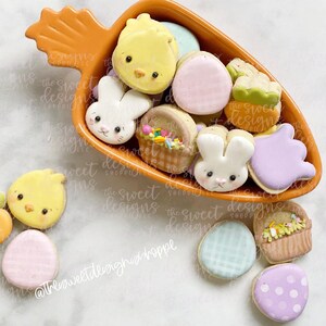 May include: A collection of Easter-themed sugar cookies in a bright orange bowl. The cookies are decorated with various designs, including chicks, bunnies, baskets, and eggs.