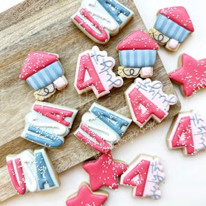 May include: A collection of red, white, and blue decorated sugar cookies with various designs, including stars, fireworks, and the number "4th".