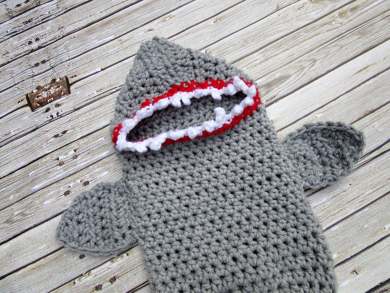 May include: Grey crocheted shark costume with a red and white mouth.