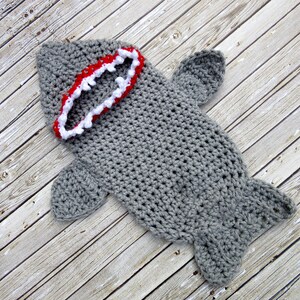 May include: Grey crocheted shark costume with a red and white open mouth.