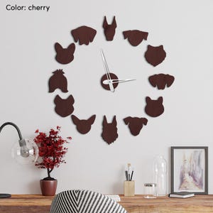 May include: Cherry-coloured wall clock featuring dog silhouettes arranged in a circle. The clock has silver hands and a central circular piece. The text "Color: cherry" is in the upper left corner. The clock is mounted on a white wall.