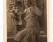 RPPC mujer sentada en la ventana con las margaritas en un vestido de estampado