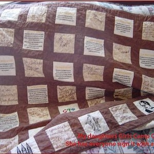 May include: A brown quilt with white squares, each square has handwritten text. The quilt is folded in half and the text on the bottom reads "My daughters Girls Camp Quilt She has everyone sign it with a Sharpie".
