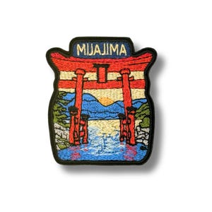 Op de afbeelding: Een geborduurde patch met een rode torii-poort in blauw water met bergen op de achtergrond. Het woord MIYAJIMA is bovenaan geborduurd met lichtgeel garen. Het ontwerp is afgewerkt met een dikke, zwart gestikte rand.