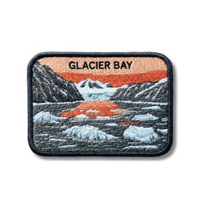 Könnte beinhalten: Ein rechteckiger gestickter Aufnäher mit einer Landschaft von Glacier Bay, dunklen Bergen, hellblauen Eisbergen im dunklen Wasser und einem leuchtend orangefarbenen Himmel. Der Text GLACIER BAY ist oben mittig in Schwarz aufgestickt.