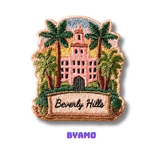 May include: Embroidered patch depicting a pink building with a tower, palm trees, and the words "Beverly Hills." The patch has a beige border and the word "BYAMO" in purple.