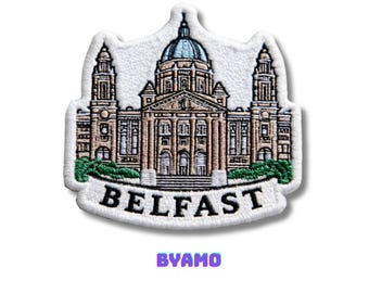 May include: Embroidered patch featuring Belfast City Hall. The patch is white with a detailed illustration of the building in shades of brown, beige, and blue. The word "BELFAST" is embroidered in black, with "BYAMO" in purple below.