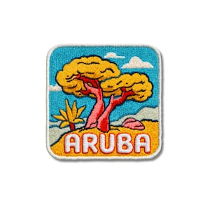 May include: A square embroidered patch featuring a landscape with two yellow trees, a small yellow plant, and a pink rock against a bright blue sky with white clouds. The word ARUBA is stitched in white letters with a red outline at the bottom.
