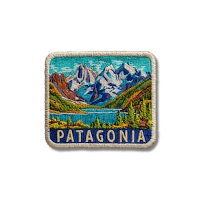 May include: A square embroidered patch featuring a landscape of snow-capped mountains, a blue lake, and green pine trees. The word PATAGONIA is stitched in cream-colored capital letters on a dark blue background at the bottom of the patch.